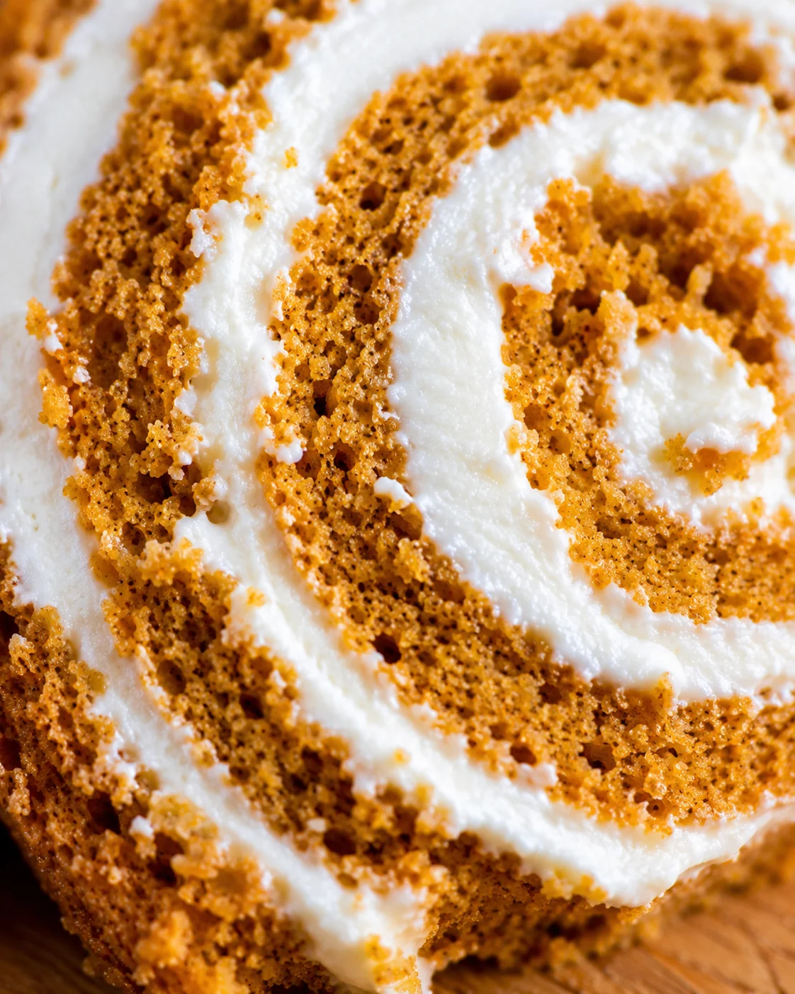 Close-up of a pumpkin roll with swirled cream cheese filling and spiced cake layers