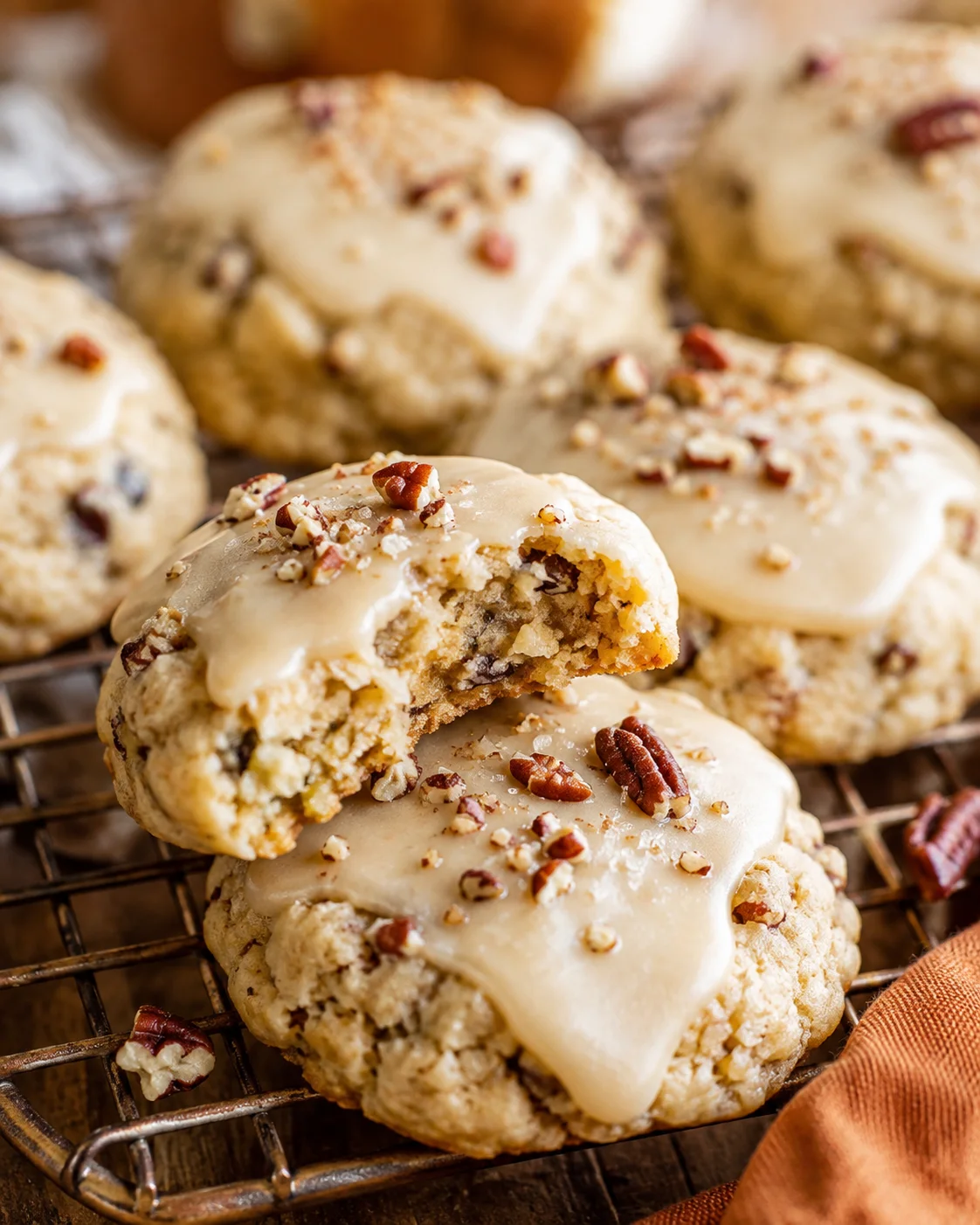 Close-up of crunchy pecan cookies topped with creamy maple glaze and chopped pecans