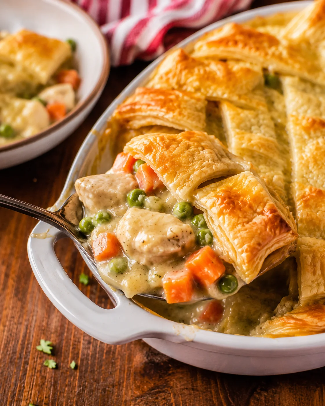 Delicious chicken pot pie casserole topped with puff pastry and fresh vegetables.