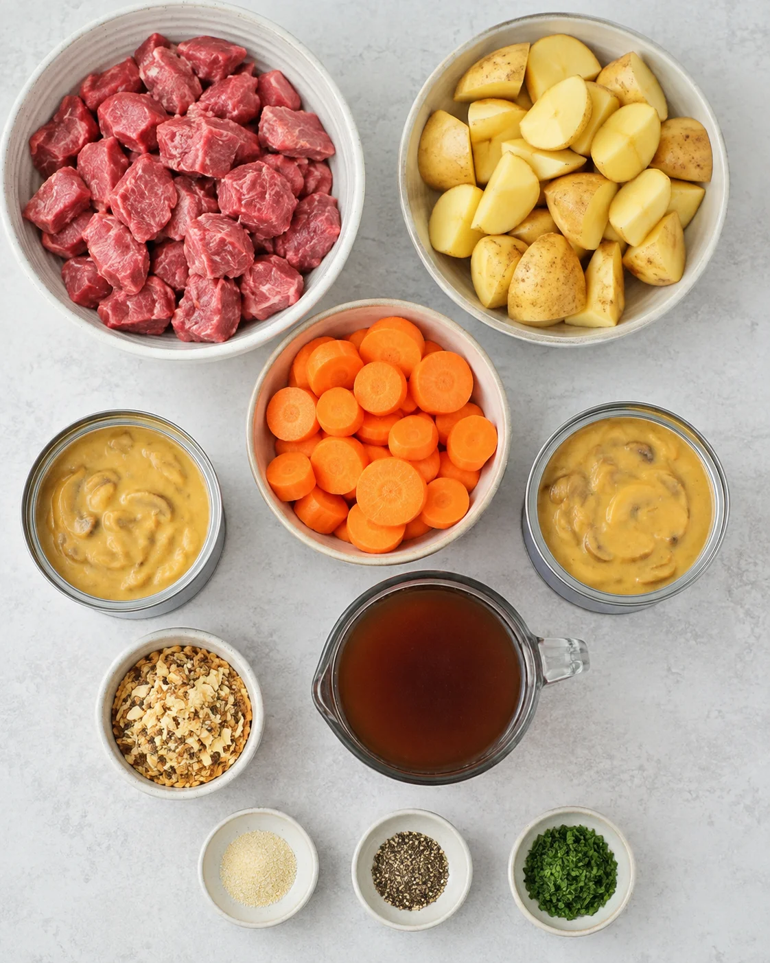 Ingredients for slow cooker beef stew including beef, potatoes, carrots, and soup.