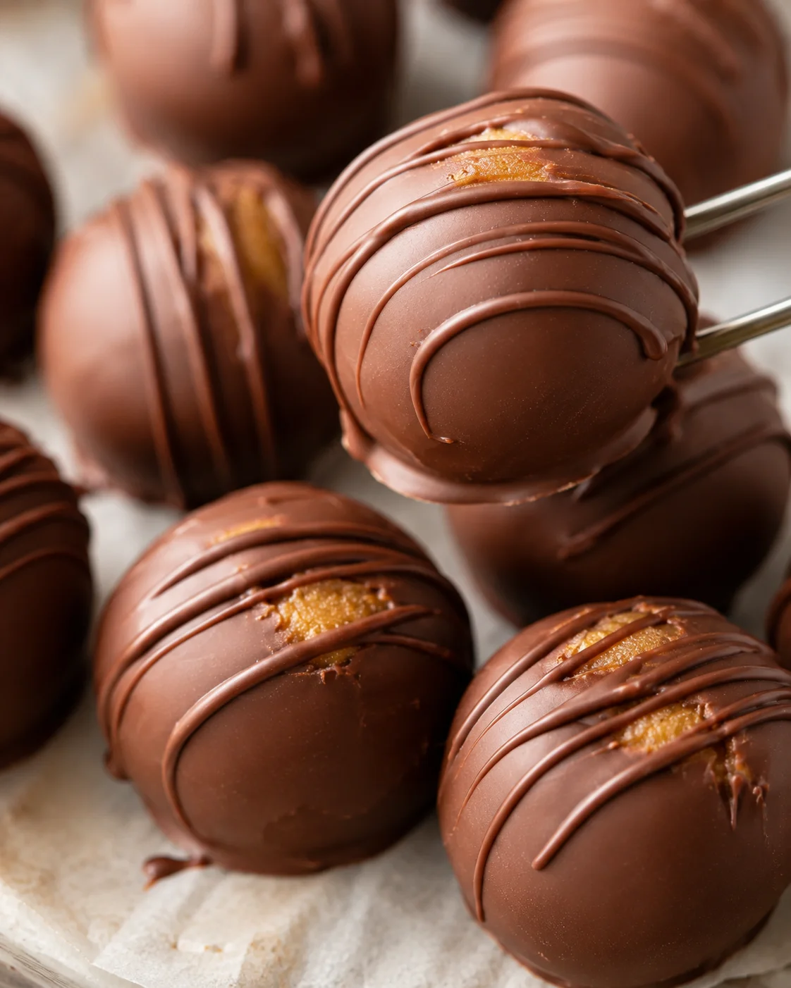 Close-up of chocolate-covered peanut butter balls with drizzled chocolate on top.