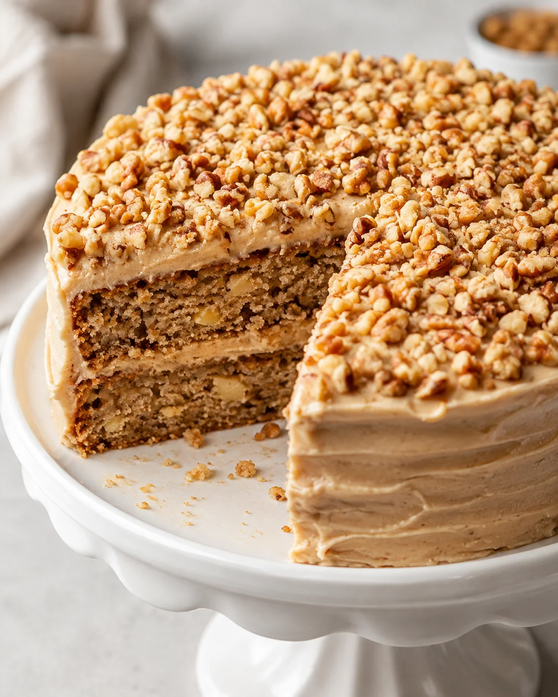 Delicious apple spice cake topped with chopped nuts and creamy frosting.