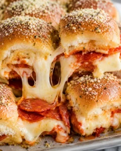 Pizza sliders with melted mozzarella stretching between soft Hawaiian rolls