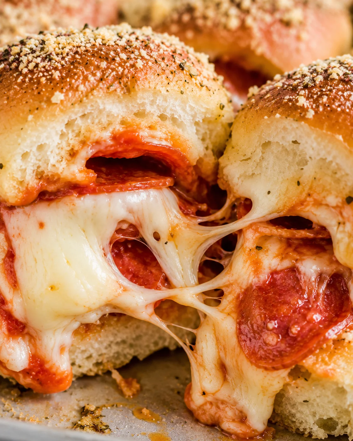 Close detail of pizza slider interior showing cheese strands and pepperoni layers