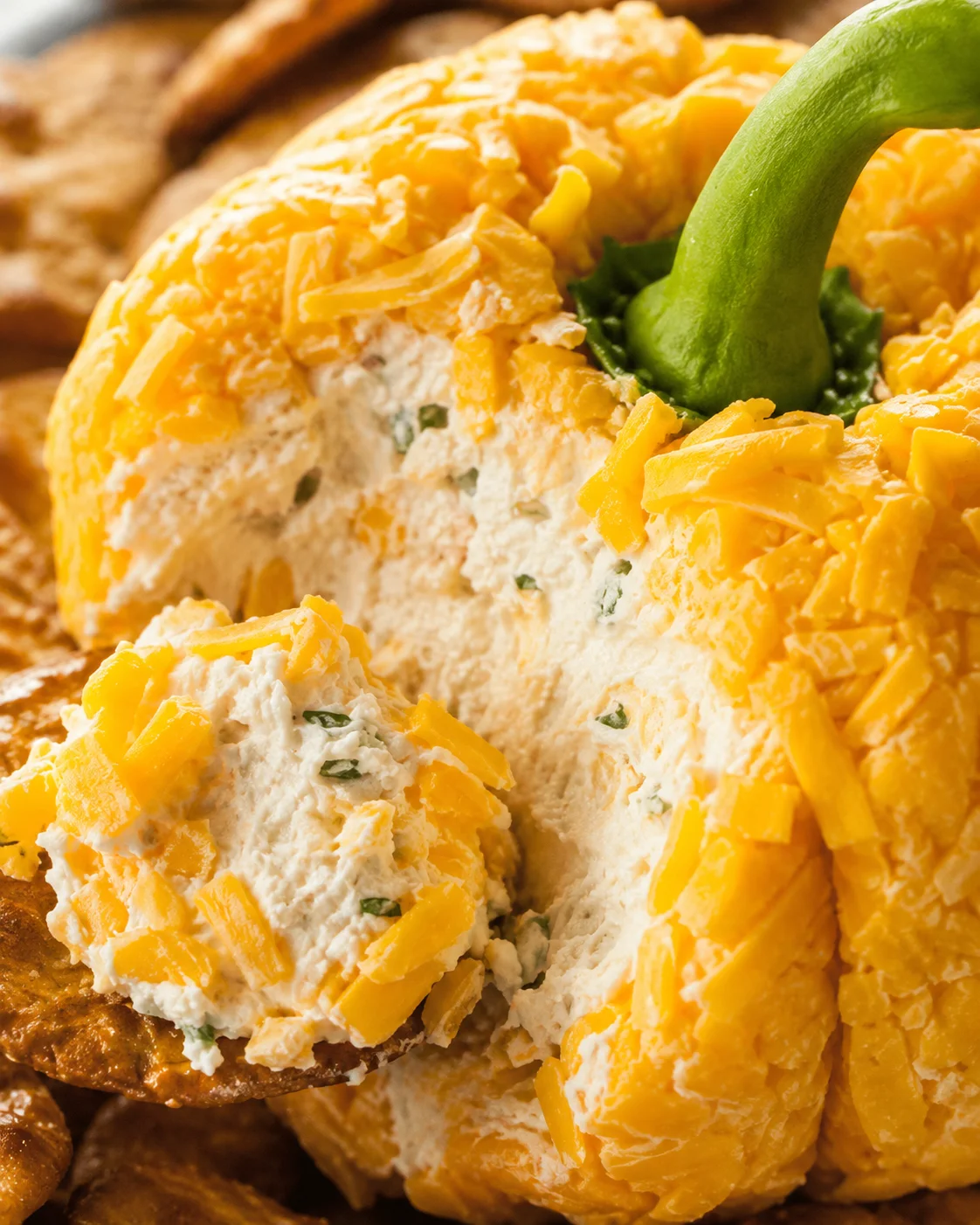Close-up of the pumpkin cheese ball interior showing creamy filling with herbs and cheddar bits