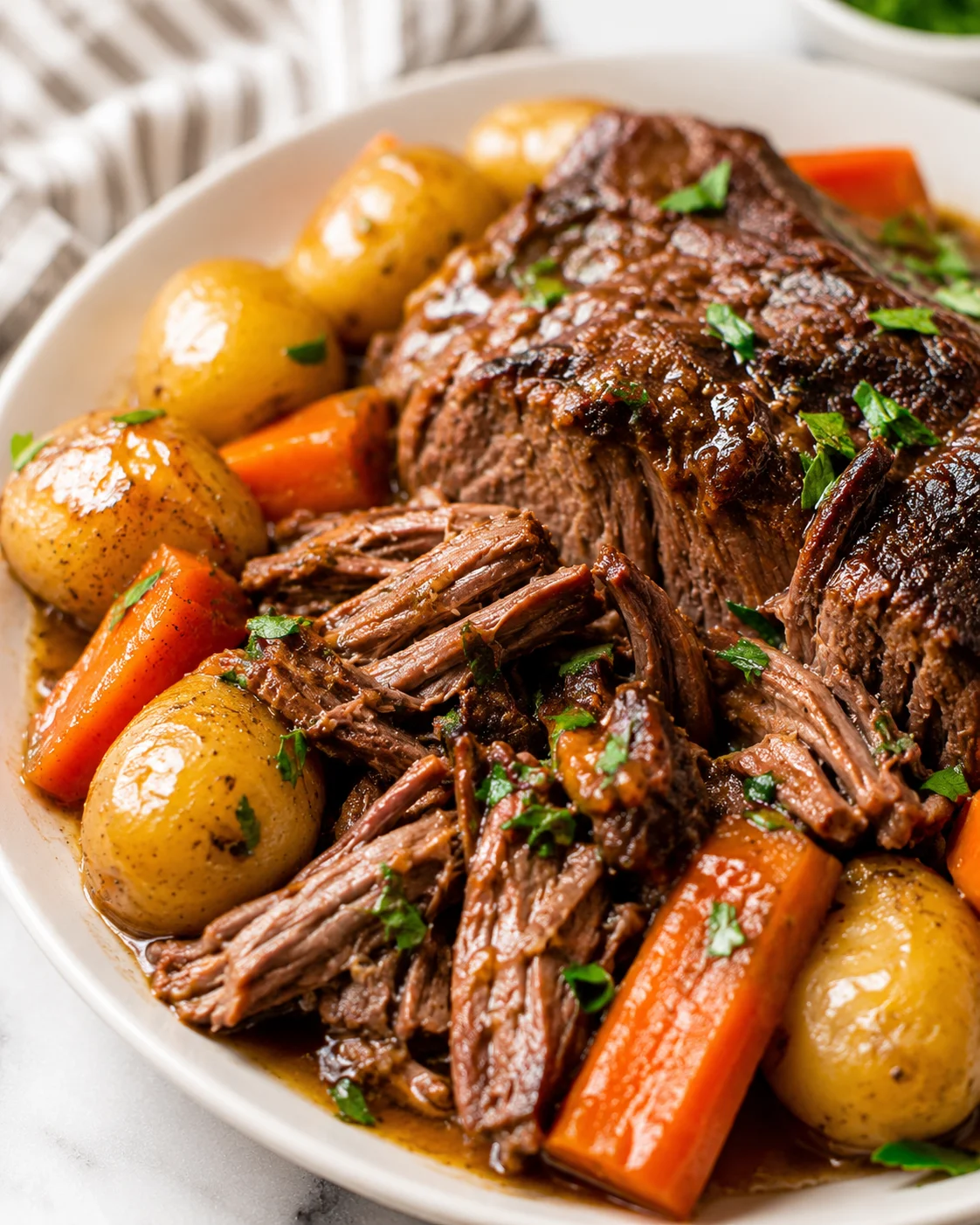 Plated slow cooker pot roast with baby potatoes and carrots in gravy